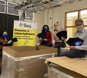 A group of people holding up donated devices for the Phone it Forward program