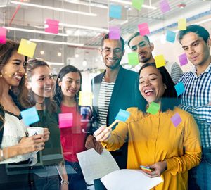 A group of people gathered in front a glass with sticky notes