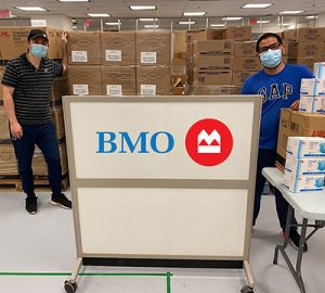 Two people standing in front of boxes of surgical masks