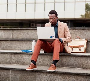 A man sitting on the steps working his laptop