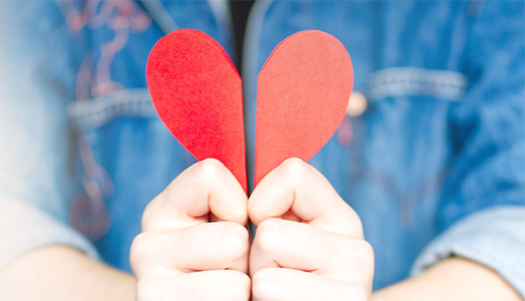 Hands holding two halves to form a red heart